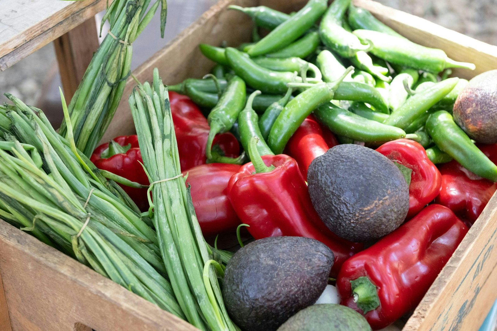 A wooden box filled with lots of different types of vegetables